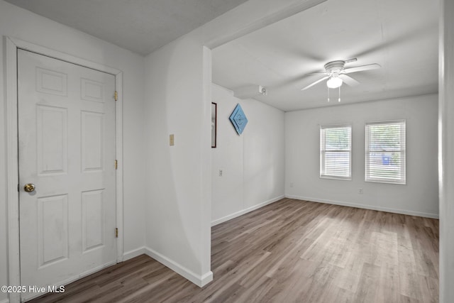 unfurnished room featuring a ceiling fan, baseboards, and wood finished floors