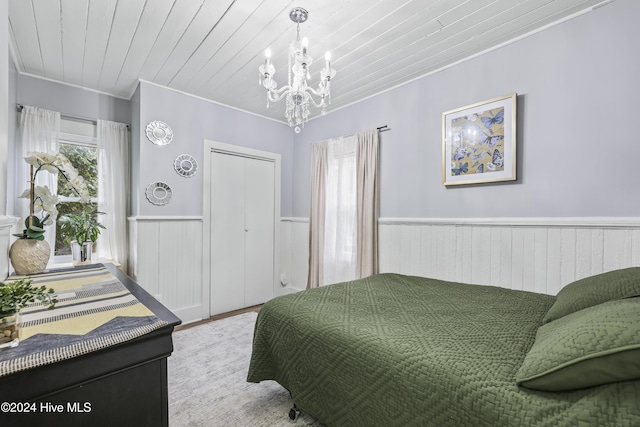 bedroom featuring ornamental molding, wood walls, a chandelier, a closet, and light wood-type flooring