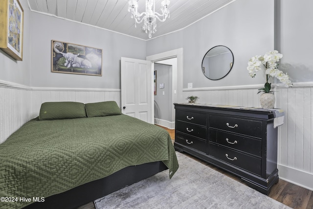 bedroom with hardwood / wood-style floors, crown molding, and a chandelier