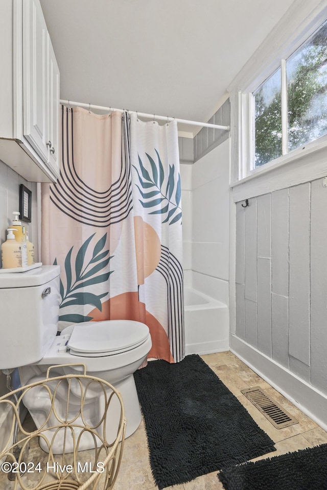 bathroom featuring toilet and shower / bathtub combination with curtain