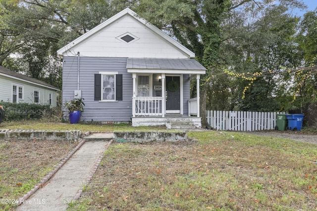 bungalow-style house featuring covered porch and a front yard