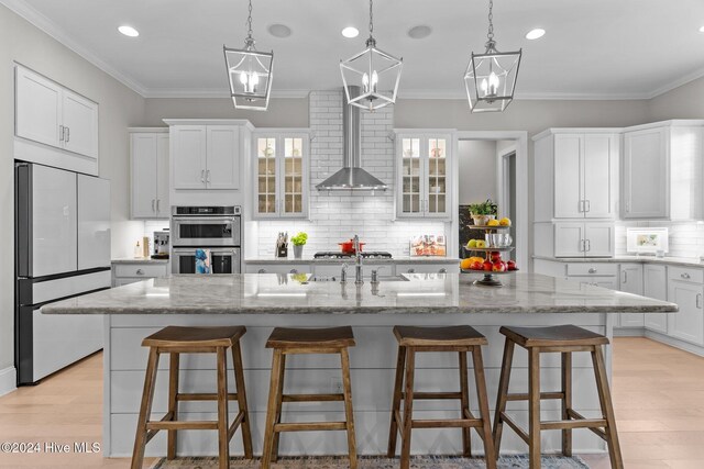 kitchen featuring white cabinets, a breakfast bar, stainless steel appliances, and a kitchen island with sink