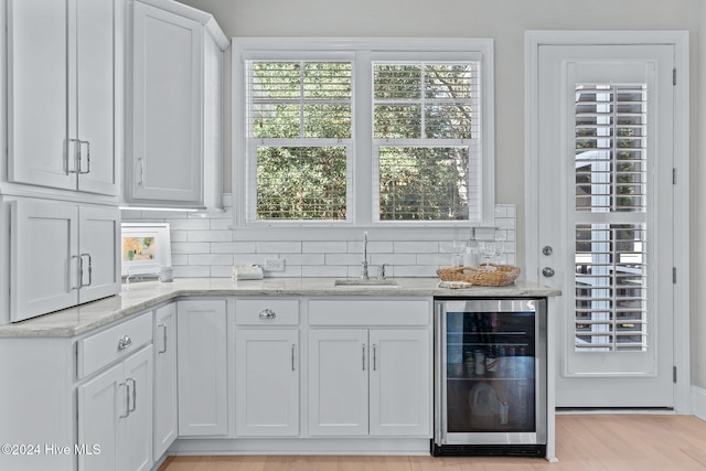 interior space featuring white cabinets, light wood-type flooring, wine cooler, and sink