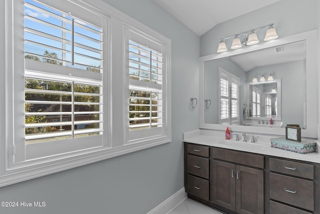 bathroom with tile patterned floors, plenty of natural light, vanity, and vaulted ceiling