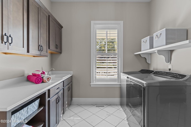 clothes washing area featuring separate washer and dryer, sink, light tile patterned floors, and cabinets