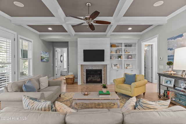 living room featuring beam ceiling, light wood-type flooring, ornamental molding, and coffered ceiling