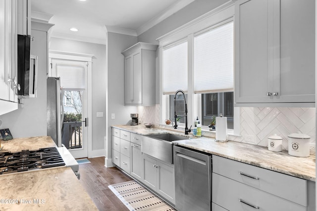 kitchen with gray cabinetry, backsplash, dark wood-type flooring, ornamental molding, and stainless steel appliances