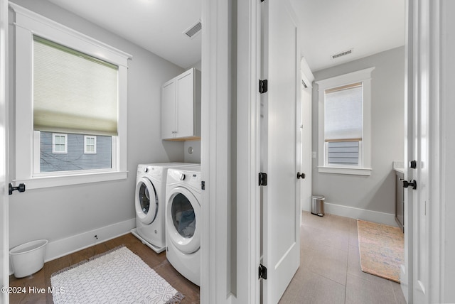 washroom with plenty of natural light, light tile patterned flooring, cabinets, and washing machine and dryer