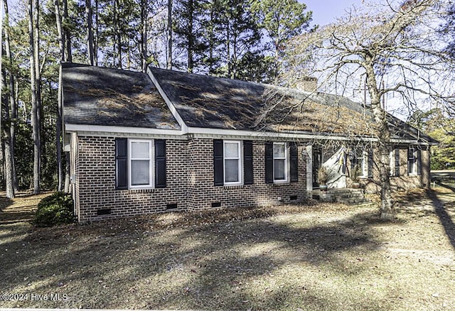 view of side of home with crawl space, a chimney, and brick siding