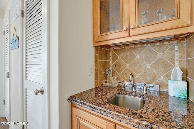 kitchen featuring sink, dark stone counters, and tasteful backsplash