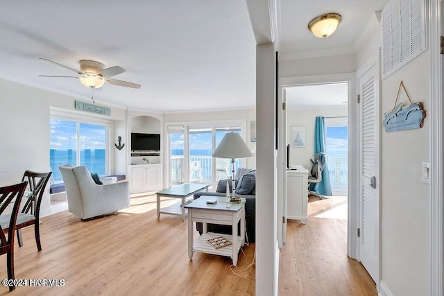 living room featuring light hardwood / wood-style floors, a wealth of natural light, crown molding, and ceiling fan