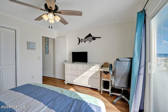 bedroom featuring ceiling fan, wood-type flooring, ornamental molding, and a closet