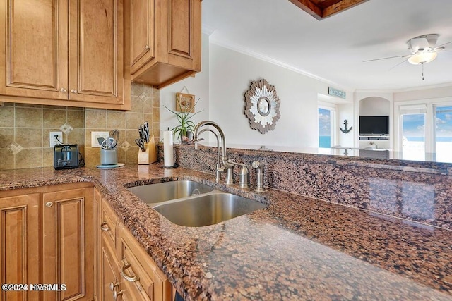 kitchen featuring backsplash, dark stone countertops, sink, and ornamental molding