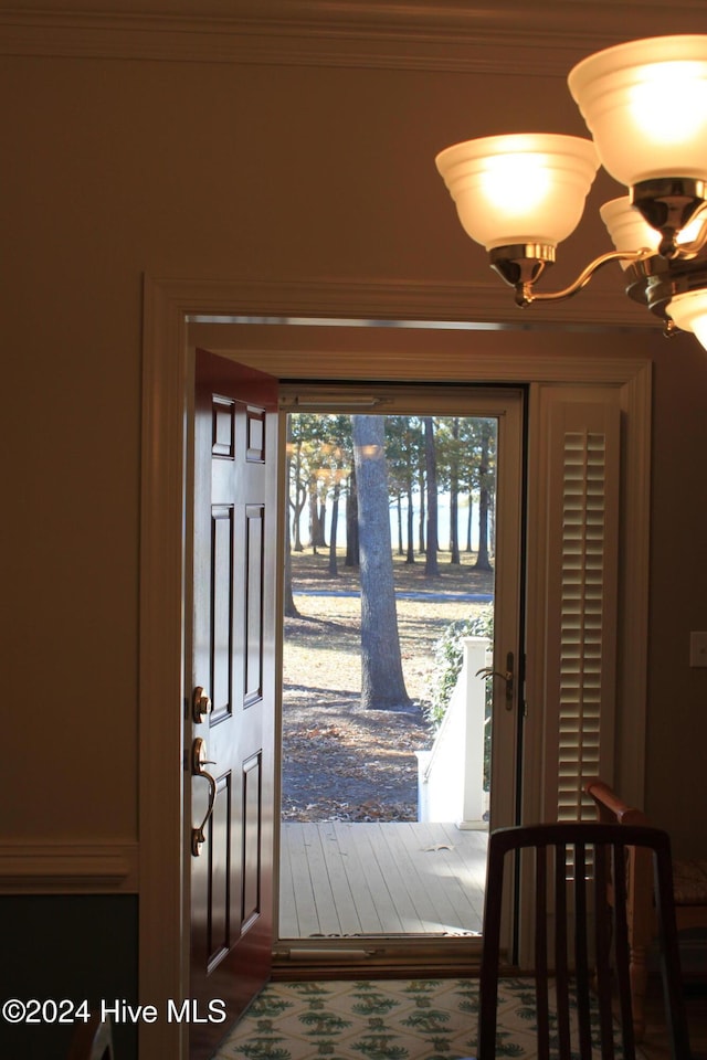 entryway with a wealth of natural light, hardwood / wood-style floors, ornamental molding, and a notable chandelier