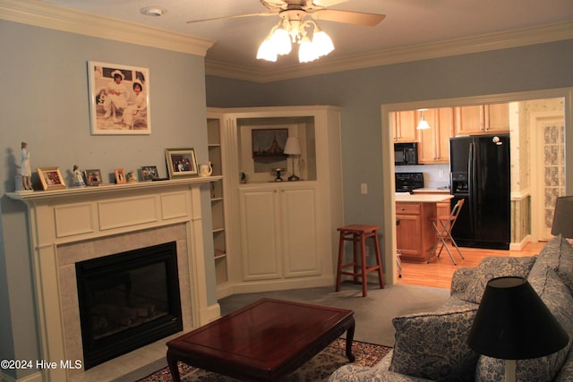 living room with a tile fireplace, light wood-type flooring, ceiling fan, and crown molding