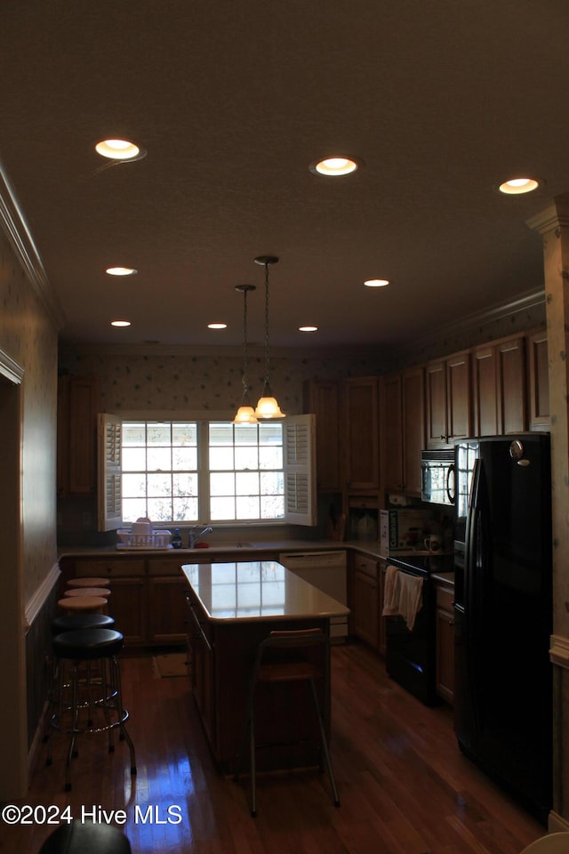 kitchen with a kitchen bar, black appliances, dark hardwood / wood-style floors, a kitchen island, and hanging light fixtures