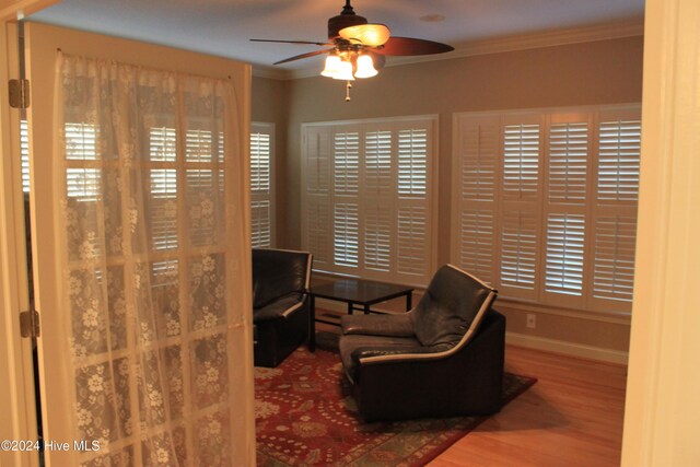 sitting room with ceiling fan, wood-type flooring, and ornamental molding