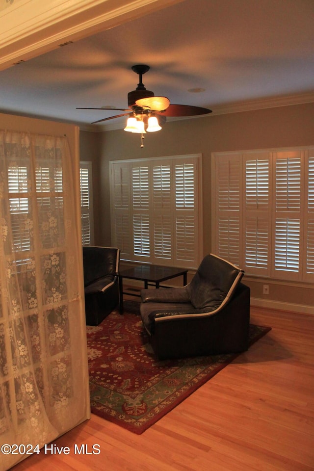 living room with hardwood / wood-style floors, ceiling fan, and crown molding