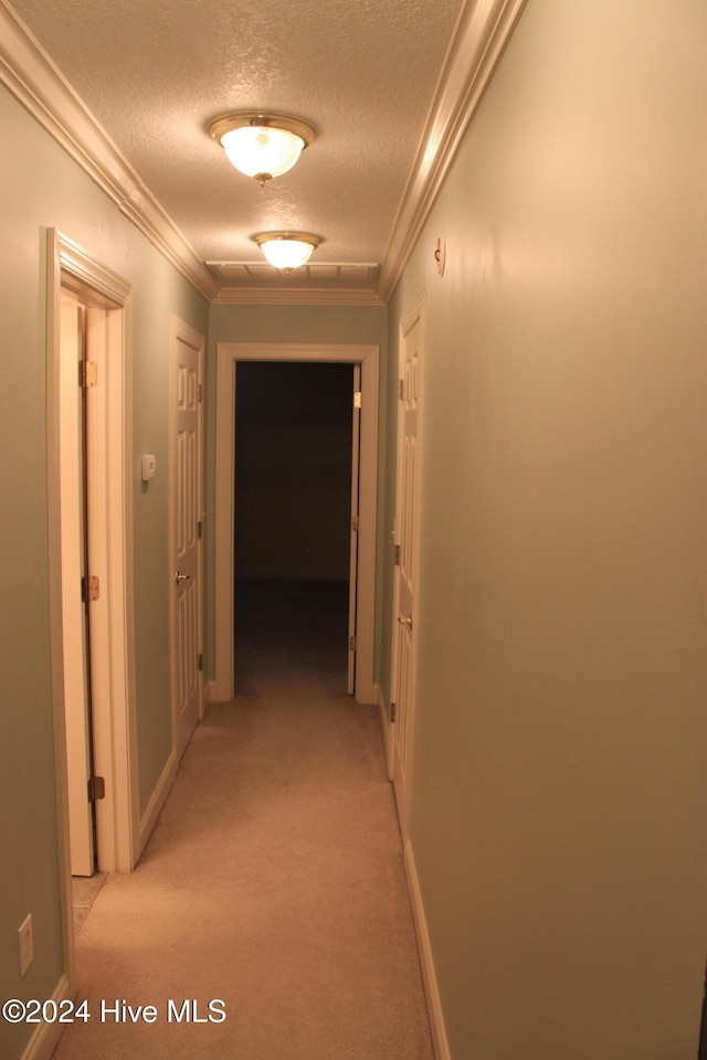 hall with a textured ceiling, light colored carpet, and crown molding