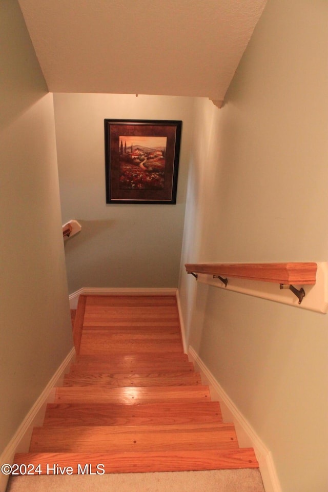 stairs featuring hardwood / wood-style floors and vaulted ceiling