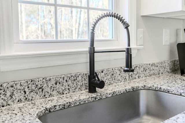 interior details featuring light stone counters and sink