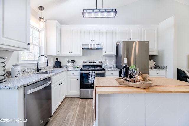 kitchen featuring white cabinetry, sink, butcher block countertops, pendant lighting, and appliances with stainless steel finishes