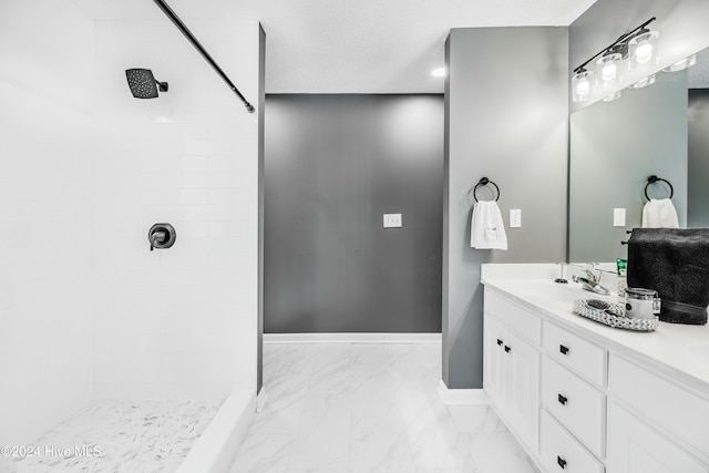 bathroom with a tile shower and vanity