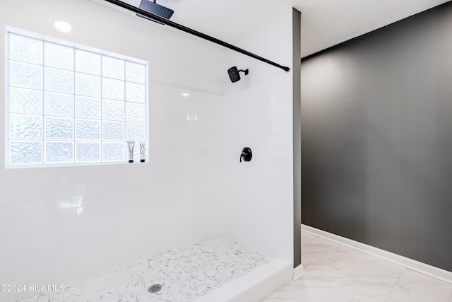 bathroom with a tile shower and a textured ceiling