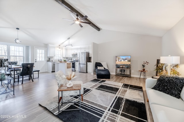 living room with lofted ceiling with beams, light hardwood / wood-style flooring, ceiling fan, and sink