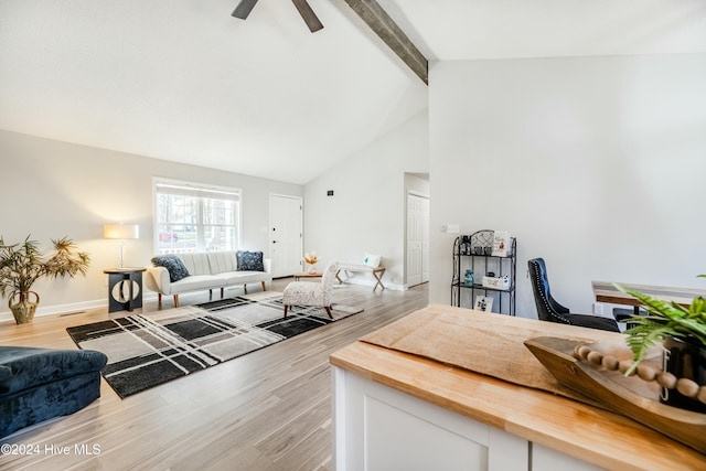 living room with ceiling fan, light hardwood / wood-style floors, and beam ceiling