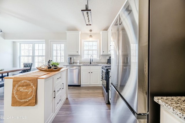 kitchen featuring sink, a healthy amount of sunlight, decorative light fixtures, and appliances with stainless steel finishes