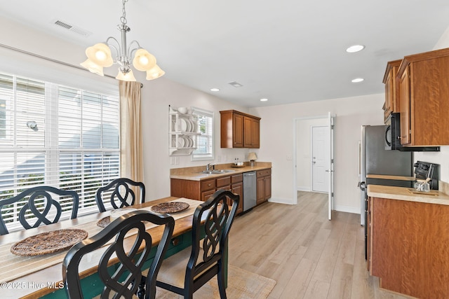 dining space featuring an inviting chandelier, sink, plenty of natural light, and light wood-type flooring