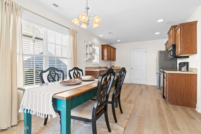 dining area featuring an inviting chandelier, light hardwood / wood-style floors, and a healthy amount of sunlight