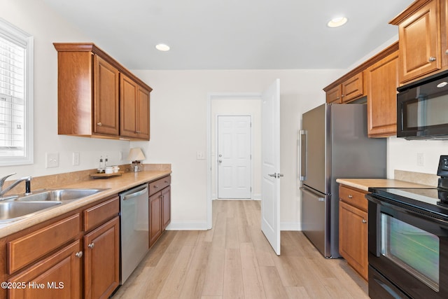 kitchen with sink, black appliances, and light hardwood / wood-style floors