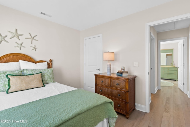 bedroom featuring ensuite bathroom and light hardwood / wood-style flooring