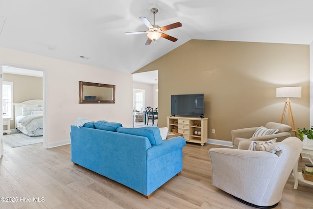 living room with vaulted ceiling, ceiling fan, and light wood-type flooring