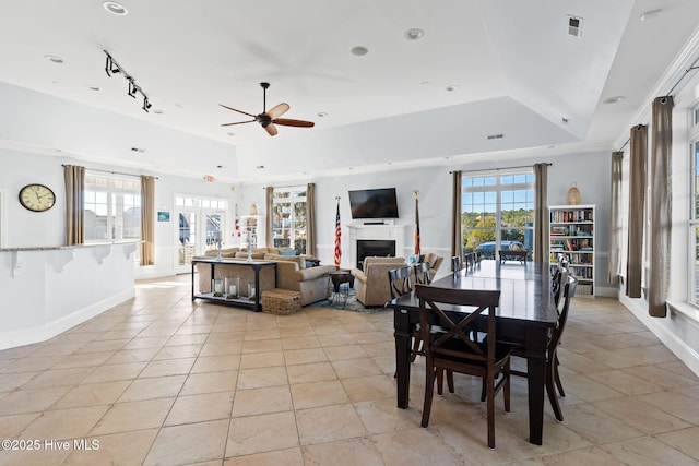 tiled dining space featuring a raised ceiling, track lighting, and ceiling fan