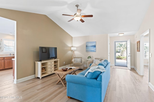 living room with ceiling fan, sink, vaulted ceiling, and light wood-type flooring