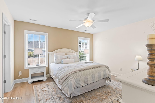 bedroom with ceiling fan, light hardwood / wood-style floors, and multiple windows