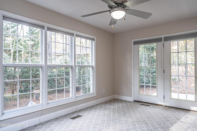 empty room featuring a wealth of natural light, ceiling fan, and a textured ceiling