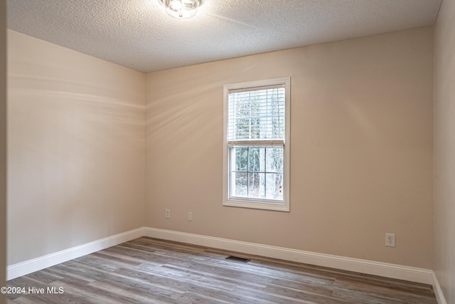 empty room with wood-type flooring and a textured ceiling