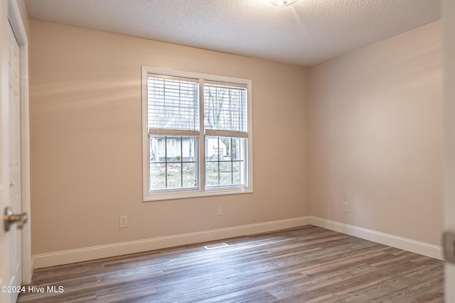 spare room featuring hardwood / wood-style floors and a textured ceiling