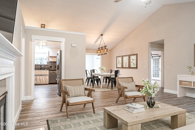 living room featuring wood-type flooring, ceiling fan with notable chandelier, lofted ceiling, and sink