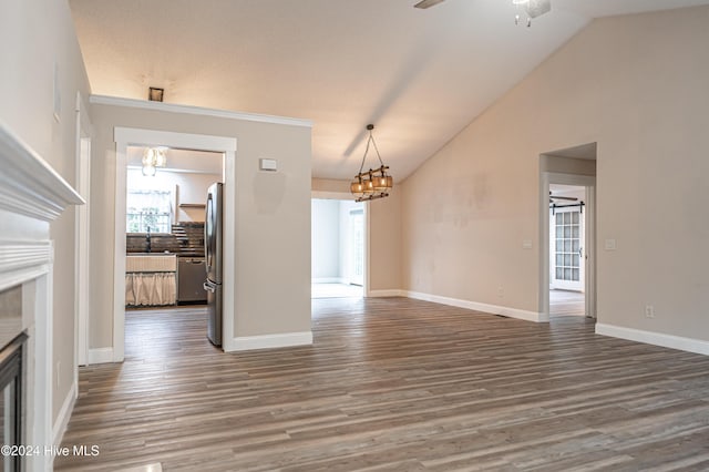 unfurnished living room featuring ceiling fan with notable chandelier, hardwood / wood-style flooring, vaulted ceiling, and sink