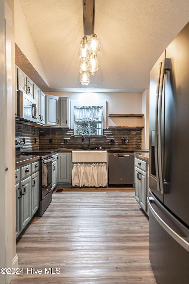 kitchen featuring lofted ceiling, sink, gray cabinets, tasteful backsplash, and stainless steel appliances