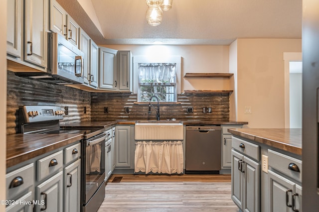 kitchen with gray cabinetry, sink, wood counters, tasteful backsplash, and appliances with stainless steel finishes