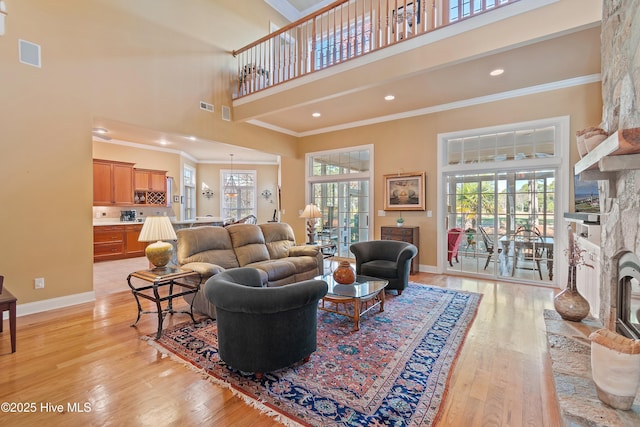 living room with a fireplace, plenty of natural light, a high ceiling, and crown molding
