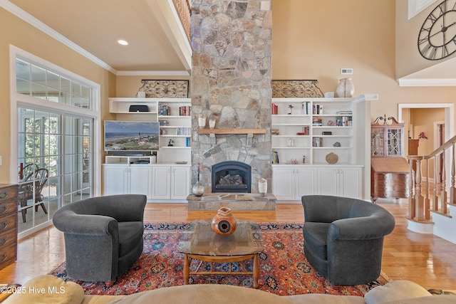 living area with a stone fireplace, wood finished floors, and crown molding