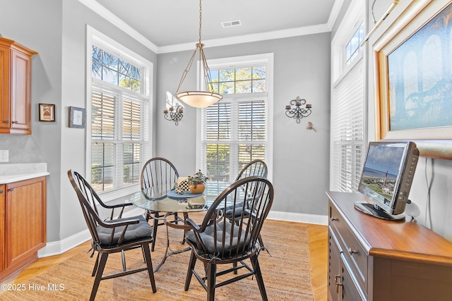 dining space featuring a wealth of natural light, ornamental molding, and light wood-style flooring