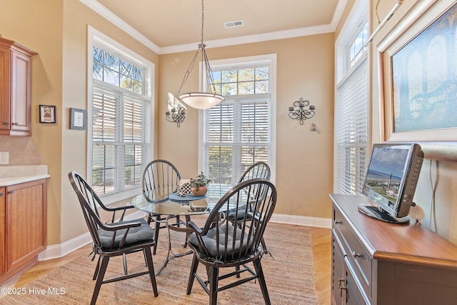 dining room with light wood-type flooring, visible vents, and ornamental molding